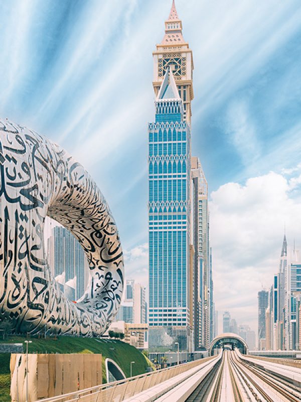 Metro railway among among glass skyscrapers in Dubai. Traffic on street in Dubai. Museum of the Future in Dubai. Cityscape skyline. Urban background.